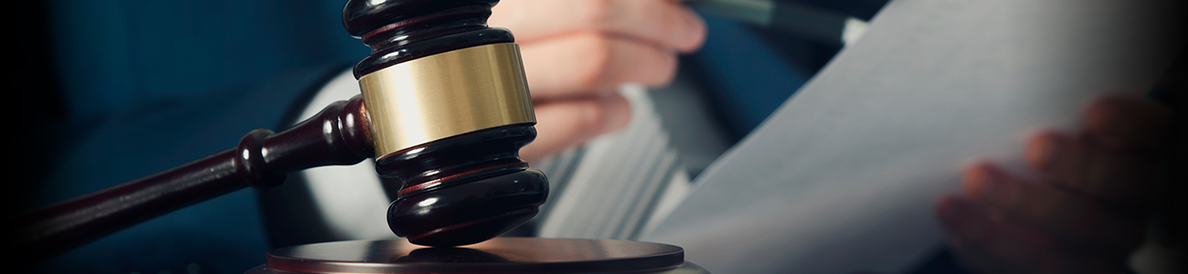 Gavel in hand with documents in the background.