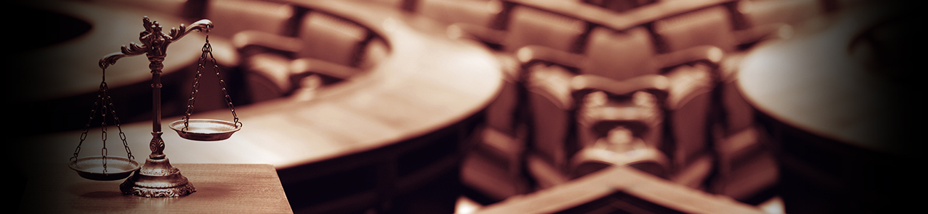 Scales of justice on a wooden table with blurred courtroom background